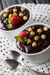 Delicious chocolate pudding with hazelnuts and raspberries close-up in a bowl. vertical