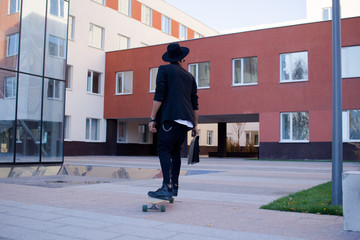 Concept of young,fast and mobile manager. Funny buisinessman on skateboard in black suit. 