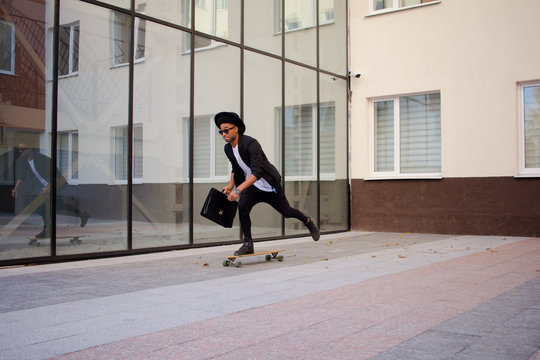 Concept of young,fast and mobile manager. Funny buisinessman on skateboard in black suit.