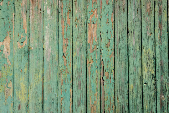 Aged board of wood with weathered paint blistering off giving brown wooden texture background