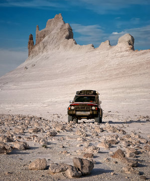 Red SUV in the desert against the backdrop of the canyon.
