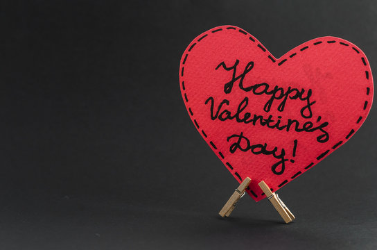 Red heart on the clothespin with the greeting happy Valentines day on dark background