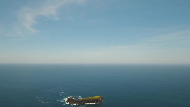 Lonely beautiful, rocky island in the sea. Aerial view Uninhabited tropical island among the ocean. Waves break on the shore of the island Travel concept. Aerial footage.