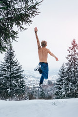 Happy man fell freedom jumping in the air in winter mountains