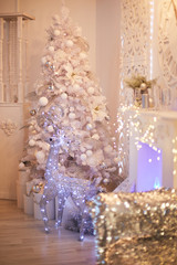 Luxurious bright living room decorated with beautiful white Christmas tree. New year's interior. Silver stag