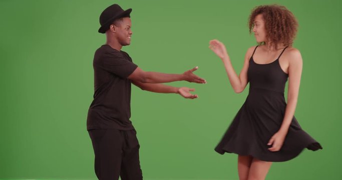 Black couple dances on green screen. On green screen to be keyed or composited. 
