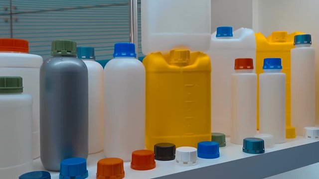 New plastic canisters and bottles of different colors from safe material for manufacturing food products cost in a row. Also shown are containers for automotive liquids and oils. Shot in motion
