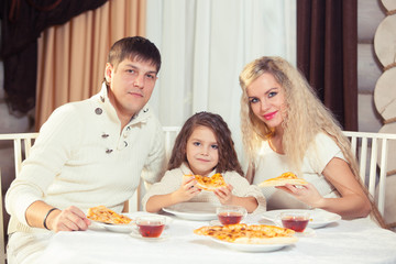 Obraz na płótnie Canvas Family eating dinner at a dining table, Round table, pizza, orange, house made of wood