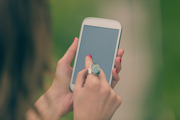 Female hands using modern cellphone / smartphone outdoors.