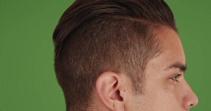 Close up side view of young millennial man with undercut standing  on green screen. On green screen to be keyed or composited. 