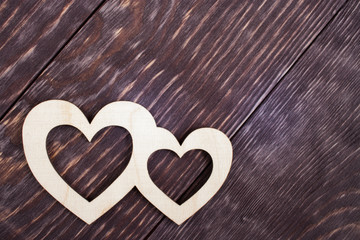 Two carved wooden hearts are lying on dark diagonal textured planks with copy space.