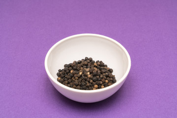 black pepper in a bowl on a colored background