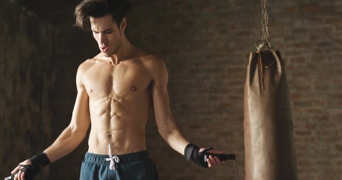  A muscular and sweaty man is training at the gym by lifting the gym weights to strengthen his muscles. Concept of: workout, workout, power, supplements, fitness