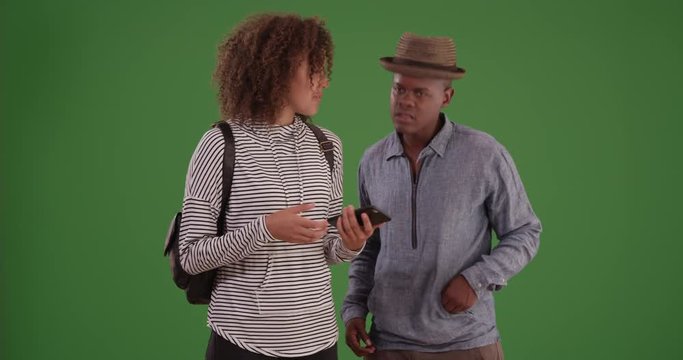 Black millennial man and woman stand waiting for a rideshare on green screen. On green screen to be keyed or composited. 