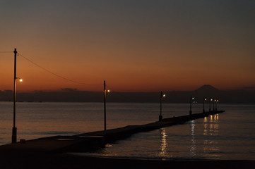 Obraz premium Mellow sunset at Haraoka-kaigan beach, Chiba-Japan. Charming wooden pier melting into the water with silhouetting Mt. Fuji.