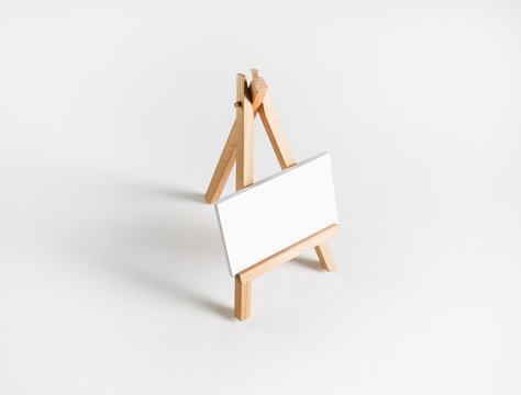 Photo of blank business card on wood holder at white paper background.