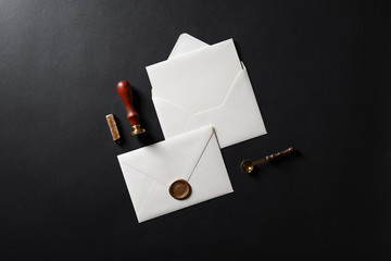 Vintage letter envelope with golden wax seal, stamp, spoon and postcard on black paper background. Mock-up for your design. Flat lay.