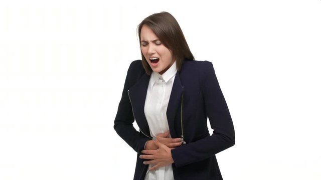 half-profile portrait of young adult woman touching stomach bending because of pain suffering from cramps having menstruation over white background in studio. Concept of emotions