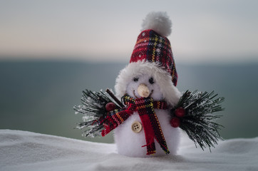 New Year Christmas concept. The snowman stands on snow with blurred nature background. White...