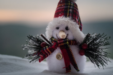 New Year Christmas concept. The snowman stands on snow with blurred nature background. White...