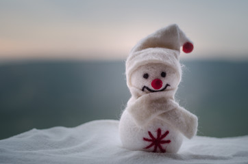 New Year Christmas concept. The snowman stands on snow with blurred nature background. White...