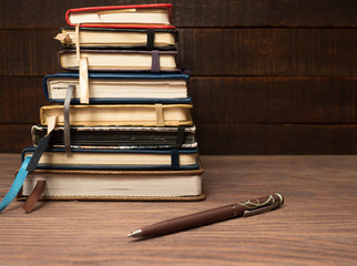 A stack of notebooks and a pen on a wooden table