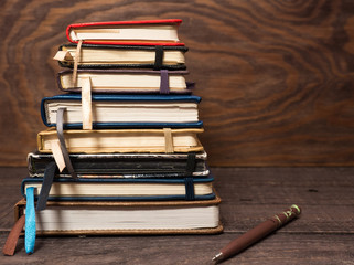 A stack of notebooks and a pen on a wooden table