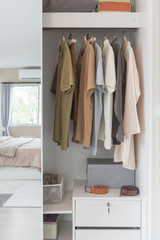 wooden wardrobe with clothes hanging on rail