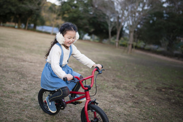 Fototapeta na wymiar 赤い自転車で遊ぶ女の子