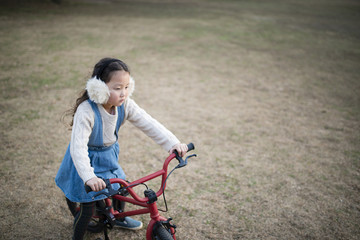 Fototapeta na wymiar 赤い自転車で遊ぶ女の子