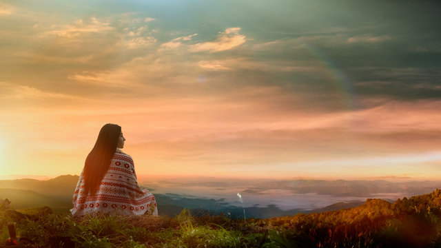 Young asian woman sitting alone outdoor with wild forest mountains on background.