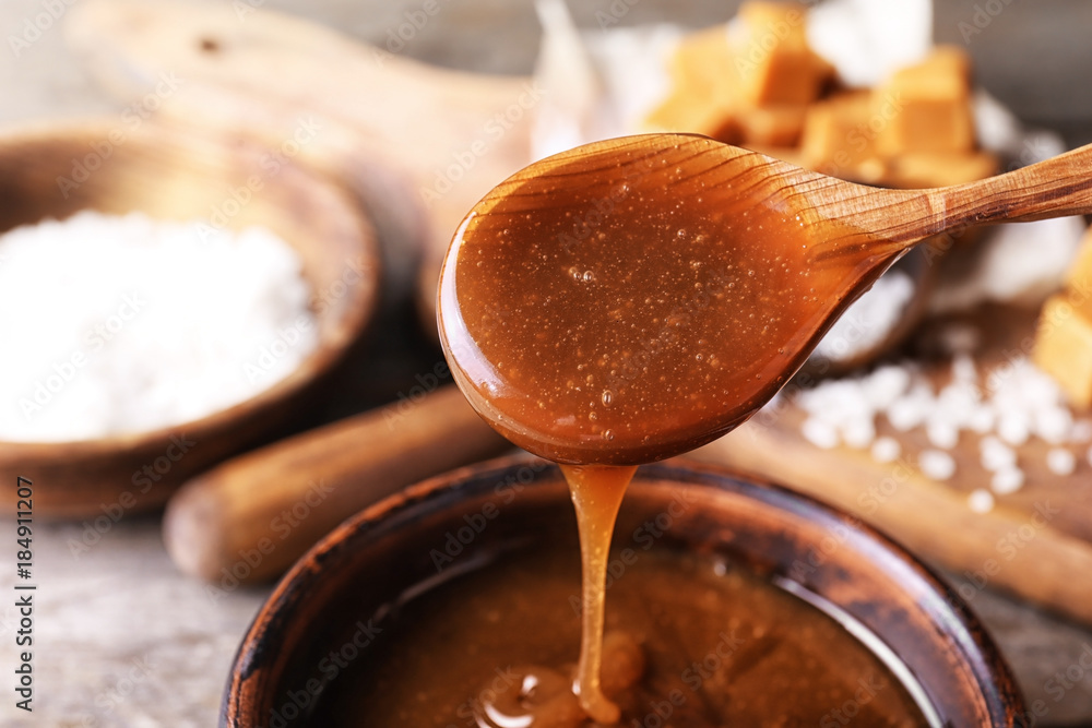 Canvas Prints spoon with tasty caramel sauce over bowl, closeup