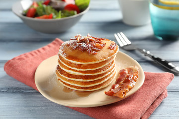 Tasty breakfast with pancakes and bacon on table