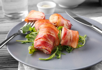 Plate with bacon wrapped chicken nuggets on table, closeup