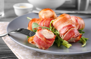 Plate with bacon wrapped chicken nuggets on table, closeup