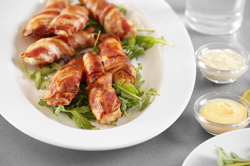 Plate with bacon wrapped chicken nuggets on table, closeup
