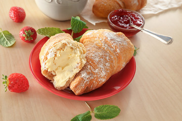 Plate with tasty croissants on wooden table