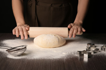 Woman rolling out puff pastry on wooden table