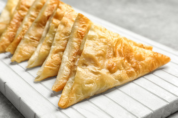 White wooden board with delicious samosas, closeup