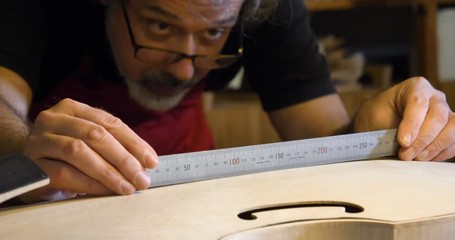 The professional violin master makes a violin with his own hands, uses a clean tree spruce, pine, glasses, planes, tunes strings. Concept: spiritual instrument, hand made, art, music, melody, sound. - Powered by Adobe