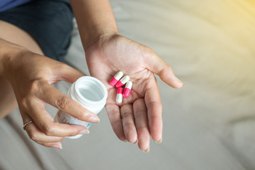 Woman hands with pills on spilling pills out of bottle