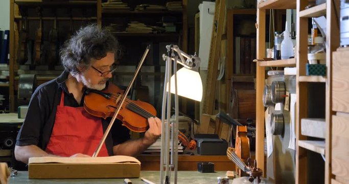 The professional violin master makes a violin with his own hands, uses a clean tree spruce, pine, glasses, planes, tunes strings. Concept: spiritual instrument, hand made, art, music, melody, sound.
