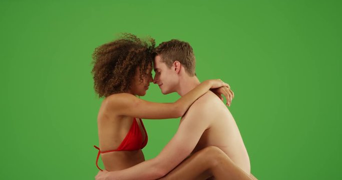 Romantic couple sitting on beach staring into each other's eyes on green screen. On green screen to be keyed or composited. 