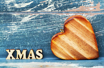 Xmas written with wooden letters and wooden heart on rustic surface
