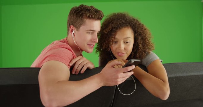 Portrait of multiracial couple listening to music on mobile phone on green screen. On green screen to be keyed or composited. 