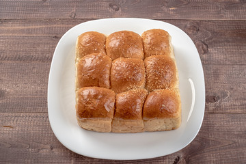 White bread in glass plate on wooden table. Top view