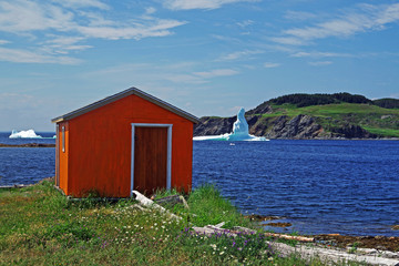 A brightly painted storage shed with icebergs in the bay