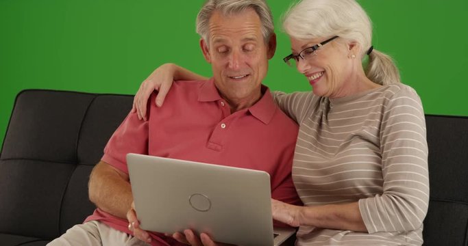 Closeup of senior couple using laptop at home on green screen. On green screen to be keyed or composited. 