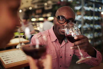 Young sommelier with glass of wine discussing its smell and taste with colleague