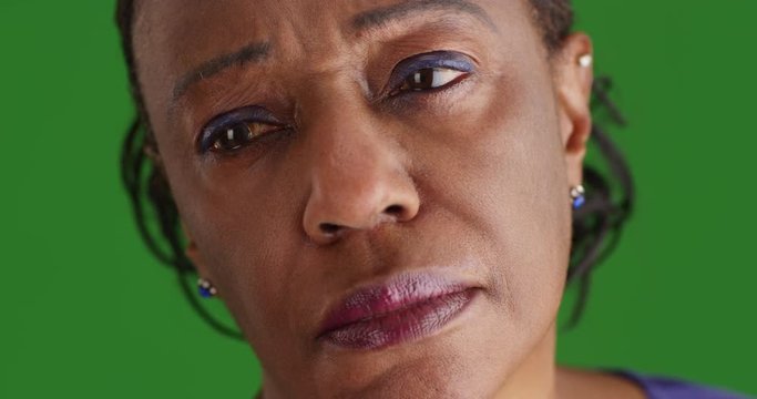 A close-up of a elderly black woman looking sad on green screen. On green screen to be keyed or composited. 